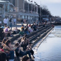 Students fill up the steps of the Memorial Union Terrace on a spring-like day. The sun is shining and the ice over the lake appears to be breaking up.